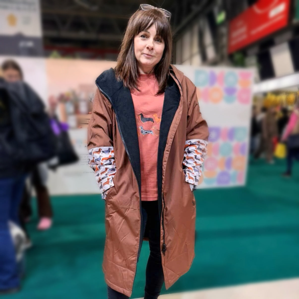 Woman wearing the DoxieBurrow waterproof dog walking robe coat at an outdoor event.