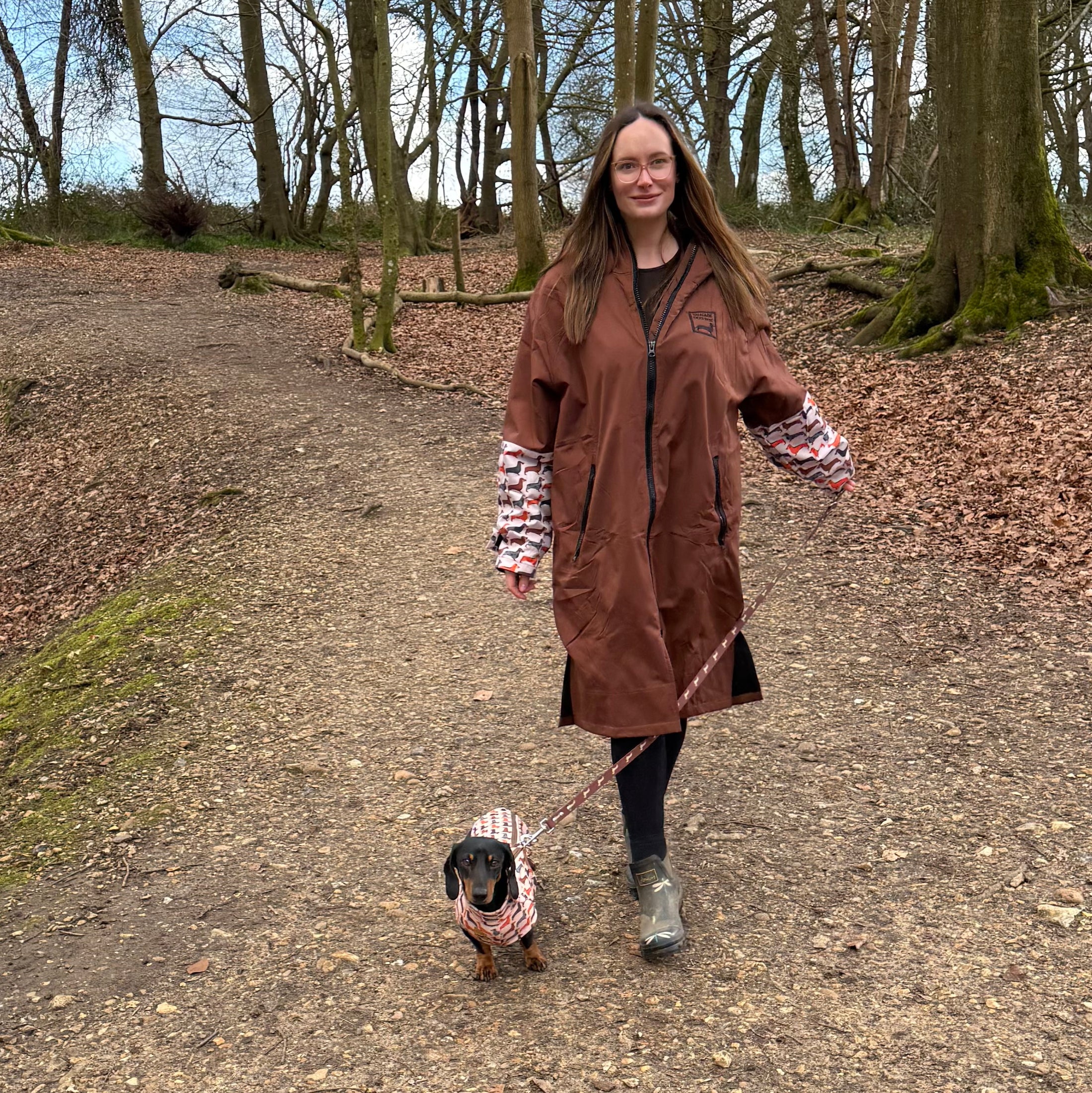 DoxieBurrow waterproof dog walking robe coat worn on a woodland walk with a dachshund.